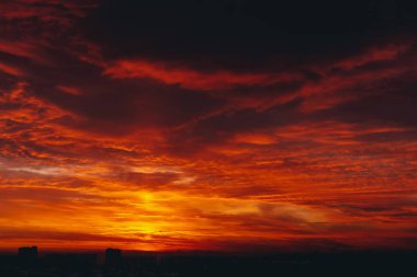 Ateşli kan vampir şafak ile Cityscape. Şehir binalarının karanlık siluetleri üzerinde Inanılmaz sıcak dramatik bulutlu gökyüzü. Turuncu güneş ışığı. Bulutlu havalarda gün doğumunun atmosferik arka planı. Kopyalama alanı.