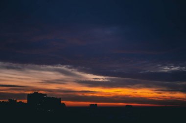Harika varirenkli ateşli şafak ile Cityscape. İnanılmaz dramatik çok renkli bulutlu gökyüzü. Şehir binası çatılarının karanlık siluetleri. Bulutlu havalarda gün doğumunun atmosferik arka planı. Kopyalama alanı.