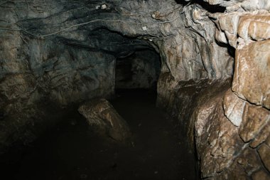 Güzel bir mağara. Karanlık zindandan manzara. Mağaranın dokulu duvarları. Yeraltı tünelinin arka plan görüntüsü. Mağaranın içinde nem var. Geziler için mağara içinde Aydınlatma.