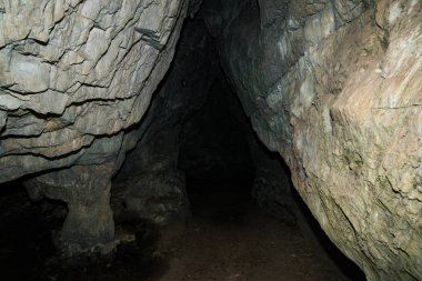 Güzel bir mağara. Karanlık zindandan manzara. Mağaranın dokulu duvarları. Yeraltı tünelinin arka plan görüntüsü. Mağaranın içinde nem var. Tünelin sonundaki ışık.