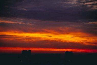 Harika varirenkli ateşli şafak ile Cityscape. İnanılmaz dramatik çok renkli bulutlu gökyüzü. Şehir binası çatılarının karanlık siluetleri. Bulutlu havalarda gün doğumunun atmosferik arka planı. Kopyalama alanı.