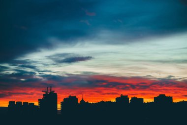 Harika varirenkli canlı şafak ile Cityscape. Şehir binalarının karanlık siluetleri üzerinde inanılmaz dramatik çok renkli bulutlu gökyüzü. Bulutlu havalarda gün doğumunun atmosferik arka planı. Kopyalama alanı.