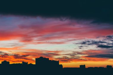Harika varirenkli canlı şafak ile Cityscape. Şehir binalarının karanlık siluetleri üzerinde inanılmaz dramatik çok renkli bulutlu gökyüzü. Bulutlu havalarda gün doğumunun atmosferik arka planı. Kopyalama alanı.