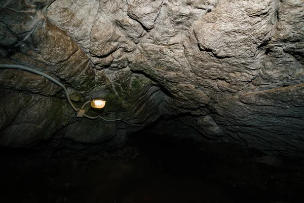 Beautiful cave. View from inside dark dungeon. Textured walls of cave. Background image of underground tunnel. Dampness inside cave. Lighting inside cave for excursions.