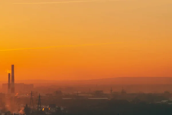 日出时建筑物剪影中的烟雾 黎明天空中的烟囱 日落时分的环境污染 城市上空的有害烟雾 雾城市背景与温暖的橙色黄色天空 — 图库照片