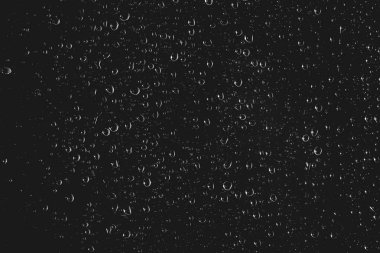 Yağmur damlalarıyla kirli pencere camı. Yağmur damlaları ile atmosferik tek renkli koyu arka plan. Damlacıklar ve lekeler kapanır. Kopyalama alanı ile makroda ayrıntılı saydam doku. Gece yağmurlu hava.