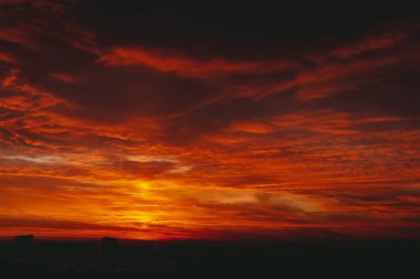 Şehir binalarının karanlık siluetleri üzerinde Amazing sıcak dramatik bulutlu gökyüzü