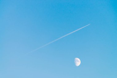 Berrak mavi gökyüzünde ay üzerinde jet yoğuşma izi