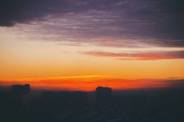 Harika varirenkli ateşli şafak ile Cityscape. İnanılmaz dramatik çok renkli bulutlu gökyüzü. Şehir binası çatılarının karanlık siluetleri. Bulutlu havalarda gün doğumunun atmosferik arka planı. Kopyalama alanı.