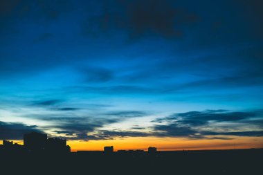 Harika varirenkli canlı şafak ile Cityscape. Şehir binalarının karanlık siluetleri üzerinde Inanılmaz dramatik mavi bulutlu gökyüzü. Bulutlu havalarda turuncu gündoğumu atmosferik arka plan. Kopyalama alanı.