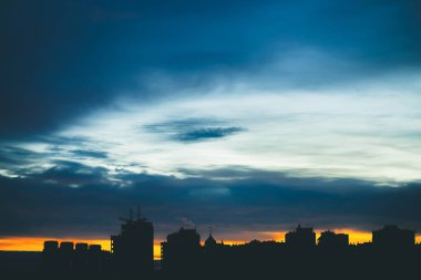 Harika varirenkli canlı şafak ile Cityscape. Şehir binalarının karanlık siluetleri üzerinde Inanılmaz dramatik mavi bulutlu gökyüzü. Bulutlu havalarda turuncu gündoğumu atmosferik arka plan. Kopyalama alanı.
