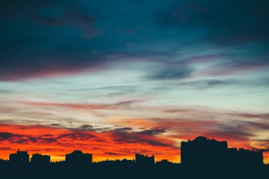 Harika varirenkli canlı şafak ile Cityscape. Şehir binalarının karanlık siluetleri üzerinde inanılmaz dramatik çok renkli bulutlu gökyüzü. Bulutlu havalarda gün doğumunun atmosferik arka planı. Kopyalama alanı.