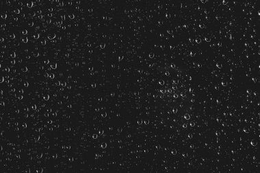 Yağmur damlalarıyla kirli pencere camı. Yağmur damlaları ile atmosferik tek renkli koyu arka plan. Damlacıklar ve lekeler kapanır. Kopyalama alanı ile makroda ayrıntılı saydam doku. Gece yağmurlu hava.
