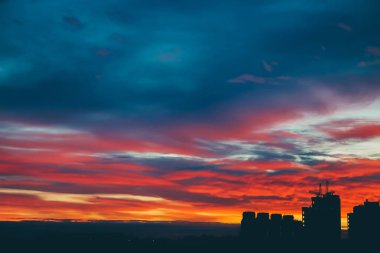 Harika varirenkli canlı şafak ile Cityscape. Şehir binalarının karanlık siluetleri üzerinde inanılmaz dramatik çok renkli bulutlu gökyüzü. Bulutlu havalarda gün doğumunun atmosferik arka planı. Kopyalama alanı.