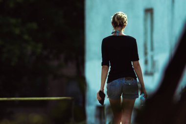 Şehirde dolaşan uzun bacaklı bir kızın dikiz manzarası.