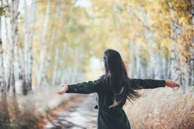 Autumn euphoria in faded tones, inspired emotional girl enjoying nature in fall forest