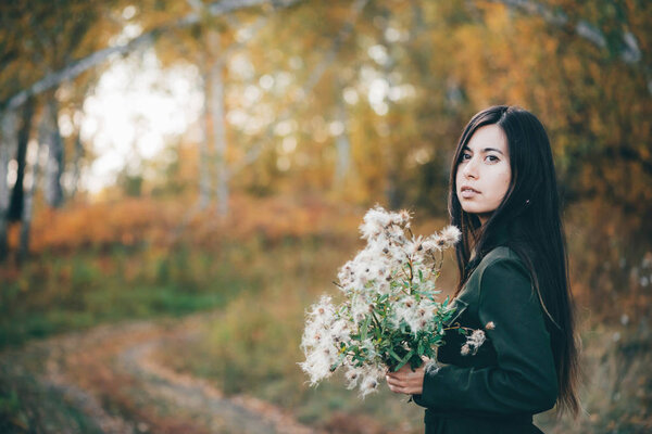 Dreamy beautiful country girl with thistle flowers bouquet on bokeh background