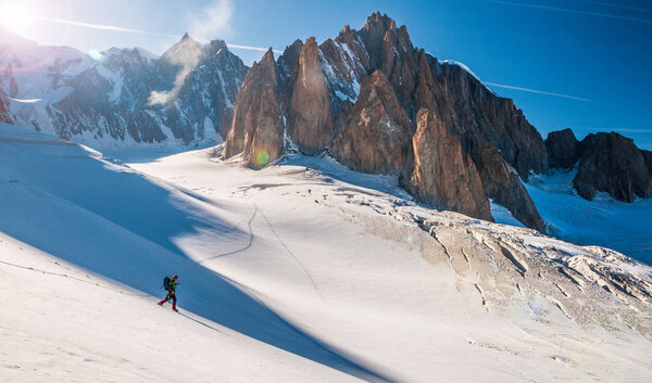 Young man descending on glacier in big mountain, Mont Blanc in background