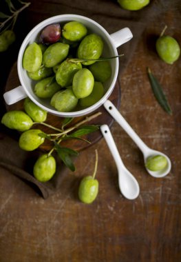 yeşil zeytin, zeytin dalı ve zeytinyağı bir koyu ahşap tahta üzerinde