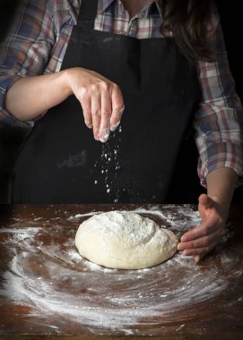 Şef pişirme hamur koyu ahşap arka plan üzerinde eller.