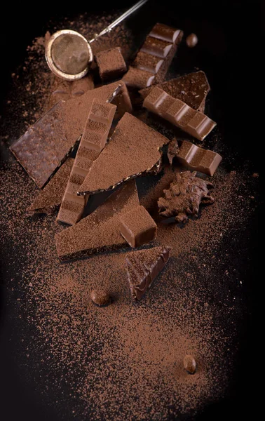 Chocoladestukjes en cacaopoeder op houten achtergrond — Stockfoto