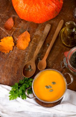 Kırsal ahşap arka planda bir kase balkabağı çorbası.