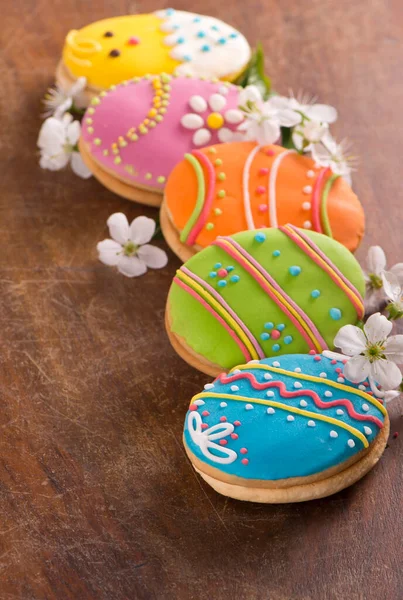 木製の表面に花で飾られたイースターエッグクッキー — ストック写真