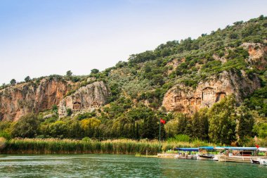 River Dalyan in Turkey with the sheer cliffs and the weathered facades of Lycian tombs cut from rock, circa 400 BC. clipart