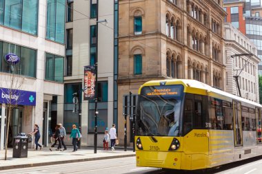 Manchester, Ingiltere-26 Haziran, 2019: Manchester Metrolink şehir merkezinde sarı tramvay.