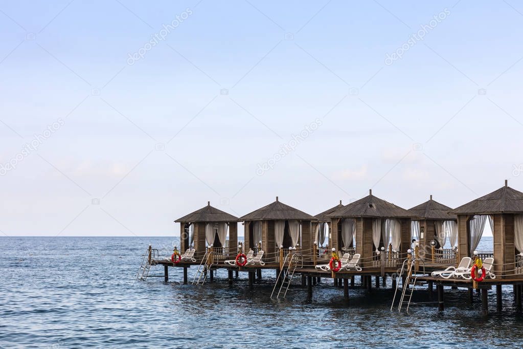Luxury beach cabanas on a wooden pier in the sea.