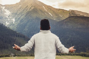 Büyük bir günlük elle ayrı oturan ve dağların güzel panorama adlı batımını genç Afrikalı Amerikalılar adam