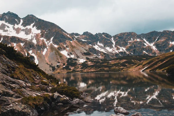 Yüksek dağlarla çevrili büyük güzel göl karla kaplı