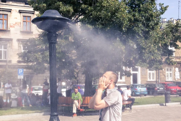 Krakow, Poland, July 28, 2018,  A young man stands under a street spray of water and washes his face escaping from the heat