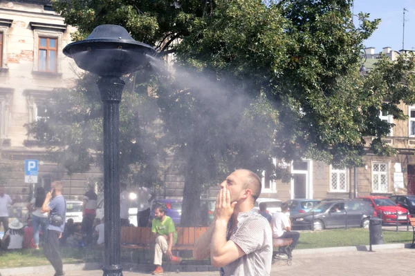 Krakow, Poland, July 28, 2018,  A young man stands under a street spray of water and washes his face escaping from the heat