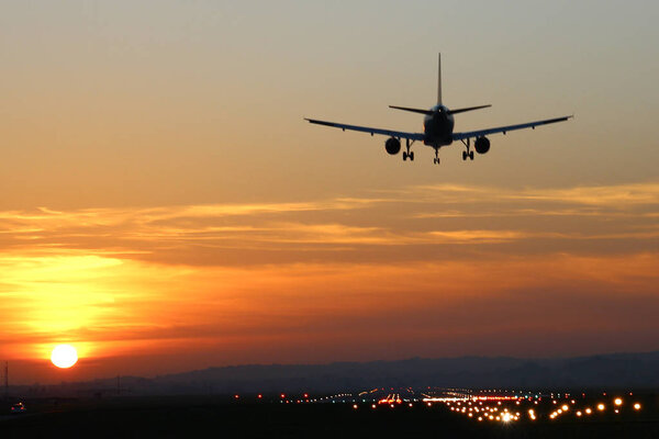 Plane landing at runway on the background of sunset