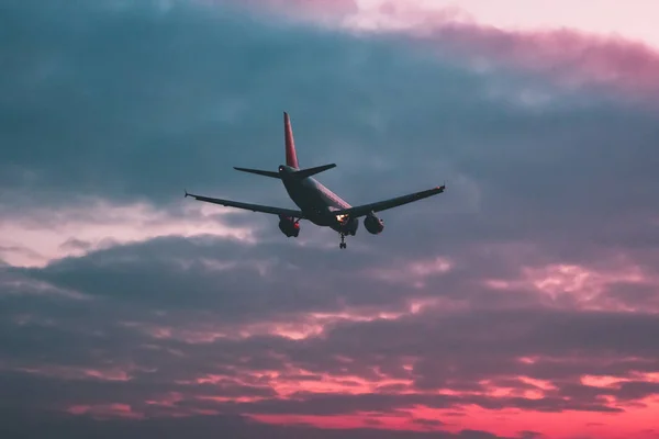 Passageiro ou avião de carga voa contra o fundo de um s vermelho — Fotografia de Stock