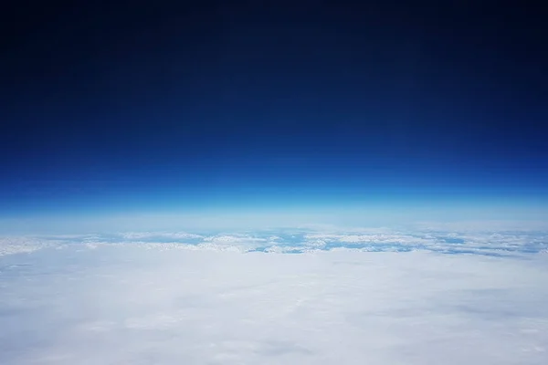 Baixa órbita terrestre - Vista de nuvens brancas e montanhas durante o voo para a órbita baixa da Terra, no topo do céu azul e espaço — Fotografia de Stock