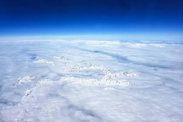 Заснеженные горы в облаках, вид с самолета — стоковое фото