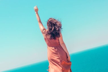 Bir kaldırdı el ile bir yaz kahverengi elbise li genç bir kız sahiptir