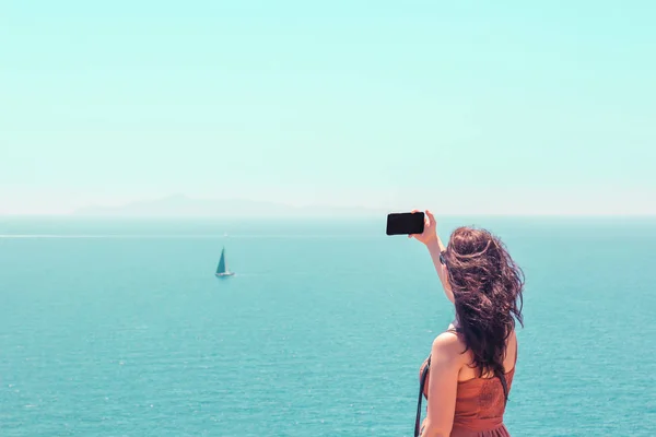 Schöne Mädchen im Kleid beim Fotografieren der Meereslandschaft Stockfoto