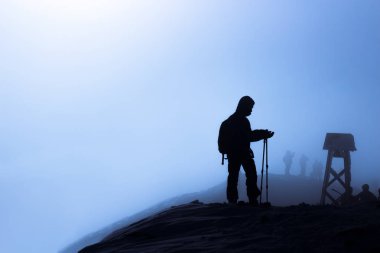 Bir dağın tepesinde bir gezginin karanlık silueti 