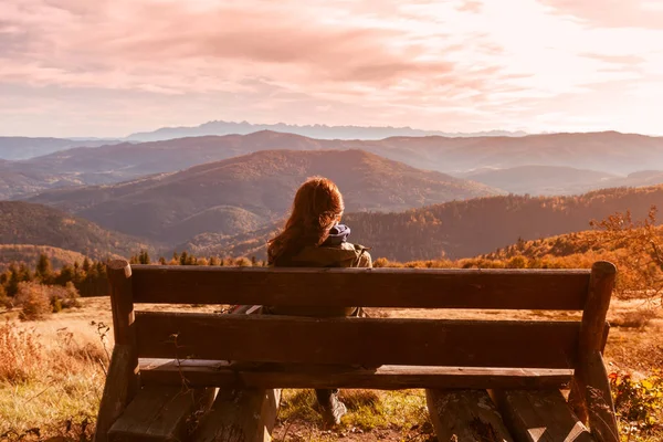 Ein junges brünettes Mädchen sitzt auf einer Bank und genießt das Panorama Stockbild