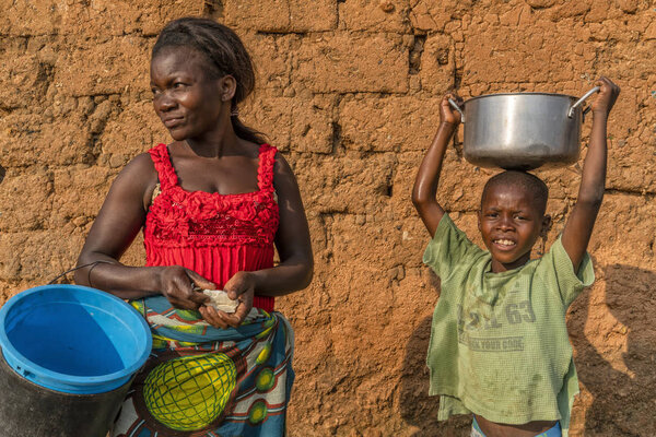 NDALATANDO/ANGOLA - 27 JUL 2017 - African mother and son in village in rural Africa with crockery.