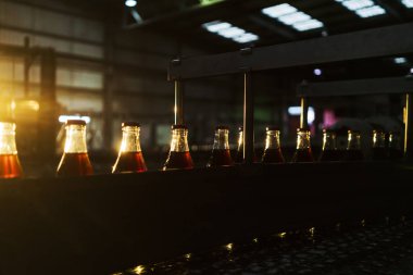 Soda factory, full bottles to roll in line with sunset light. clipart