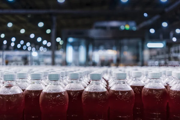 Bottles of red soda in the factory line.