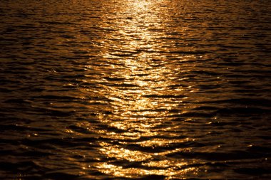 Nehir suyu dramatik günbatımı tonları ile.