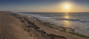 Beautiful panoramic sunset on the wild beach of the Namibe Desert. Angola. Africa. clipart