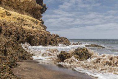 Kanyon Namibe çöl sahilde. Vahşi plaj kayalar ve deniz suyu sıçrama. Afrika. Angola. Namibe.