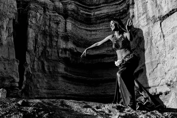 Young girl dancing to the famous arabic dance, belly dance with canyons of Namibe desert in background, extreme body and facial emotion. Namibe. Africa. Angola. Bw version