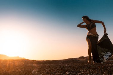Ünlü Arap oryantal dans için dans kadın. Namibe kurak çöl düz gün batımı ile. Afrika. Angola.